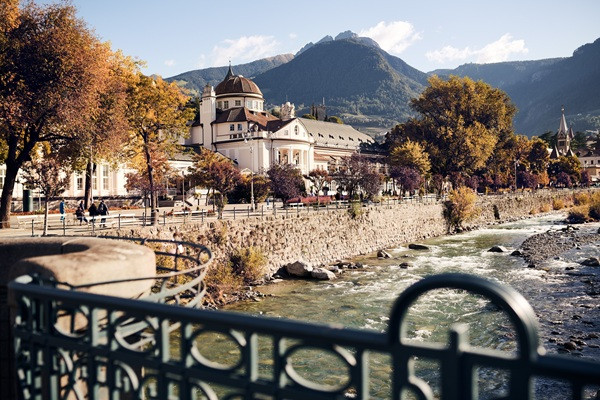 Kurhaus e passeggiata lungo il Passirio a Merano Il Kurhaus di Merano lungo il Passirio, con alberi autunnali e montagne sullo sfondo