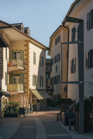 A spasso nel centro di Lana Vicolo di Lana con facciate decorate, persiane e tavolini di un caffè