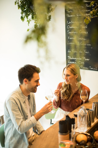 Tempo per un aperitivo Una coppia gusta vino bianco e stuzzichini al bancone di un bar