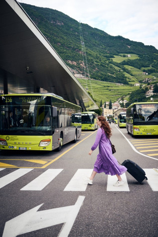 In autobus alla scoperta dell’Alto Adige Donna con trolley tra gli autobus verdi all’autostazione di Bolzano