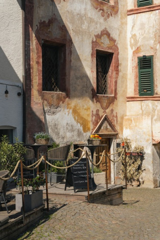 Un vicolo di Lana Vicolo lastricato a Lana con una facciata dipinta e la piccola terrazza di un locale