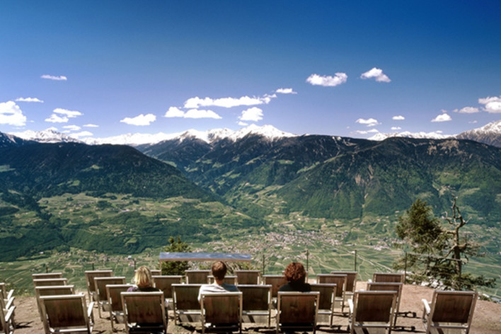 Knottnkino a Verano Visitatori seduti su poltrone in legno al Knottnkino a Verano, con vista sulla Val d’Adige e sulle montagne
