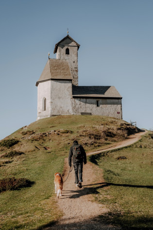 Chiesetta di San Vigilio Escursionista con un cane sul sentiero verso la chiesetta di San Vigilio, su un dosso erboso a Monte San Vigilio